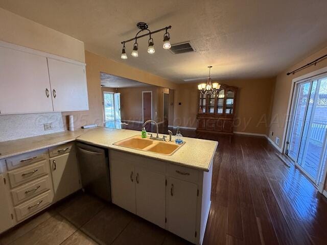 kitchen with a peninsula, light countertops, a sink, a notable chandelier, and dishwasher