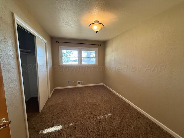 unfurnished bedroom with a closet, visible vents, carpet flooring, and baseboards