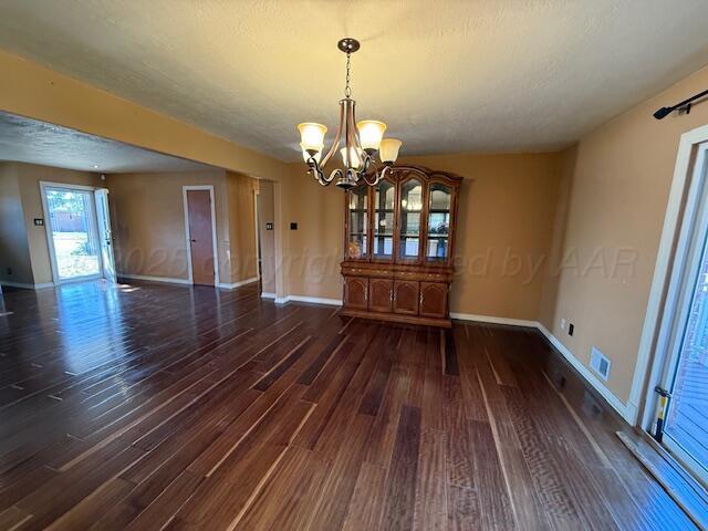 unfurnished dining area with visible vents, baseboards, wood finished floors, and an inviting chandelier