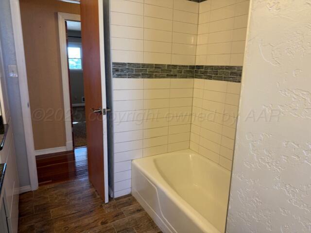 bathroom with baseboards, a textured wall, and wood finished floors