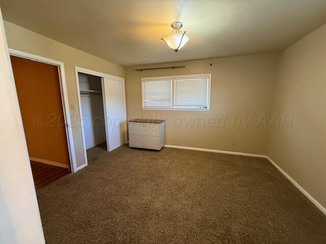 unfurnished bedroom with baseboards, carpet flooring, and a closet