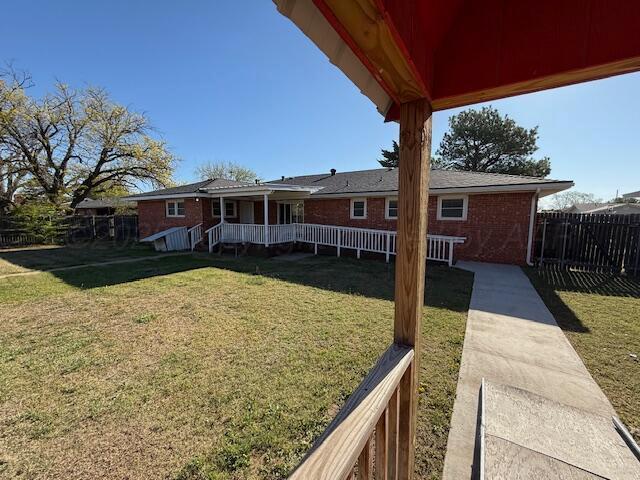 back of house featuring fence, brick siding, and a yard