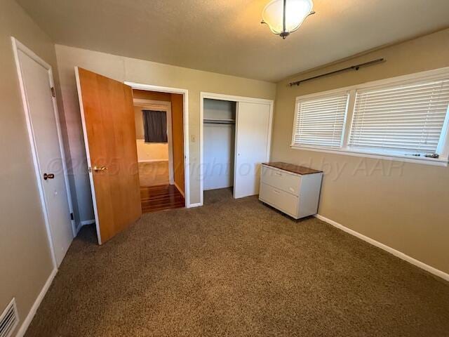 unfurnished bedroom featuring carpet floors, a closet, baseboards, and visible vents