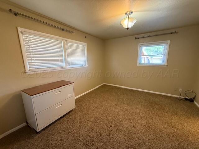 unfurnished room featuring dark colored carpet and baseboards