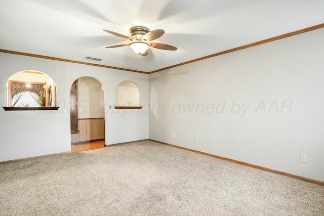 unfurnished room with crown molding, carpet flooring, baseboards, visible vents, and ceiling fan