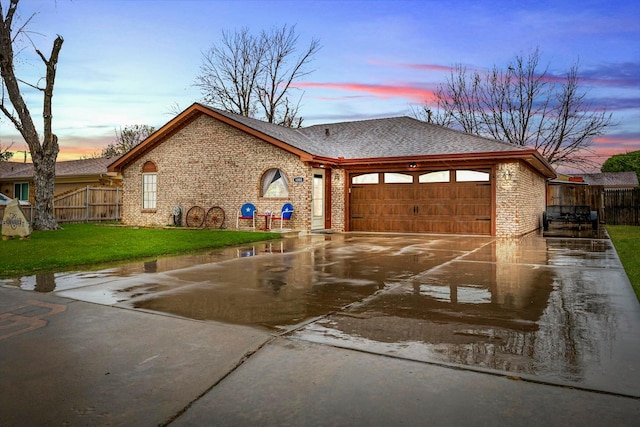 view of front facade with an attached garage, brick siding, fence, and concrete driveway