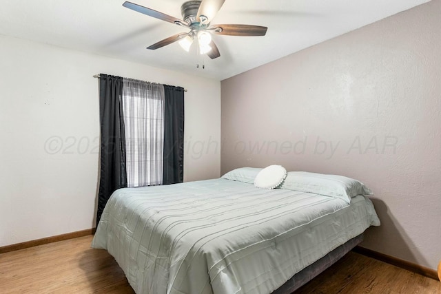 bedroom featuring baseboards, wood finished floors, and a ceiling fan