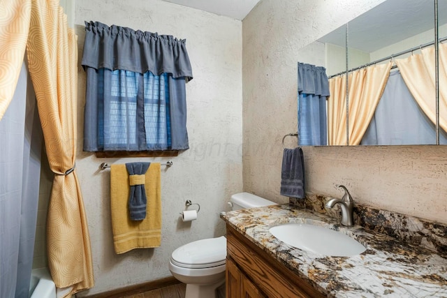 full bath with a textured wall, toilet, and vanity