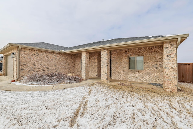 view of front of property with a garage, brick siding, and roof with shingles