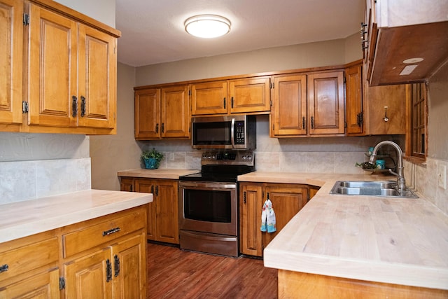 1215 S Main St, Hereford, TX 79045 - kitchen with appliances with stainless steel finishes, a sink, brown cabinets, light countertops, and dark wood finished floors