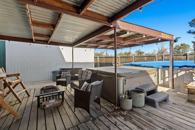 wooden terrace featuring a fire pit, fence, a fenced in pool, and a hot tub