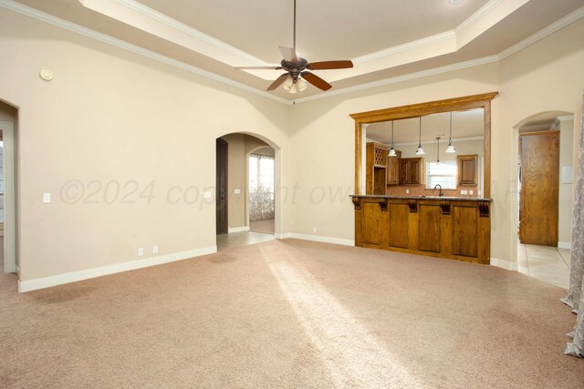 8620 Cortona Dr, Amarillo, TX 79119 - unfurnished living room featuring arched walkways, a raised ceiling, crown molding, a sink, and plenty of natural light