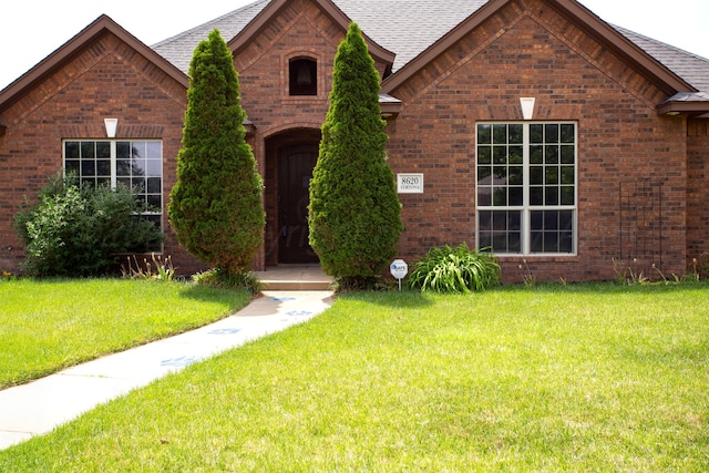 8620 Cortona Dr, Amarillo, TX 79119 - tudor home with brick siding, a front lawn, and roof with shingles