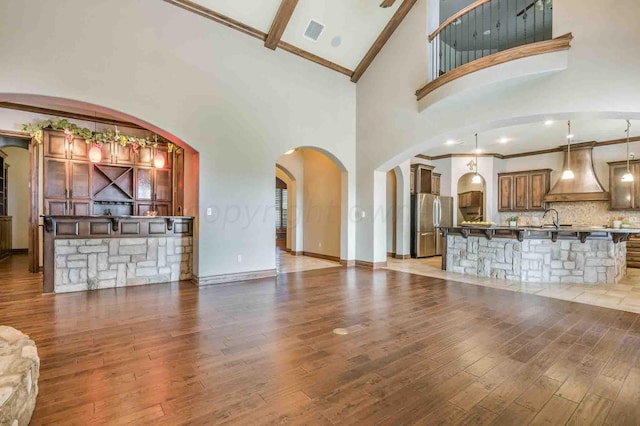 unfurnished living room with crown molding, sink, light hardwood / wood-style flooring, and high vaulted ceiling