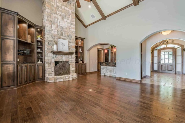 unfurnished living room featuring a fireplace, dark hardwood / wood-style flooring, beamed ceiling, and high vaulted ceiling