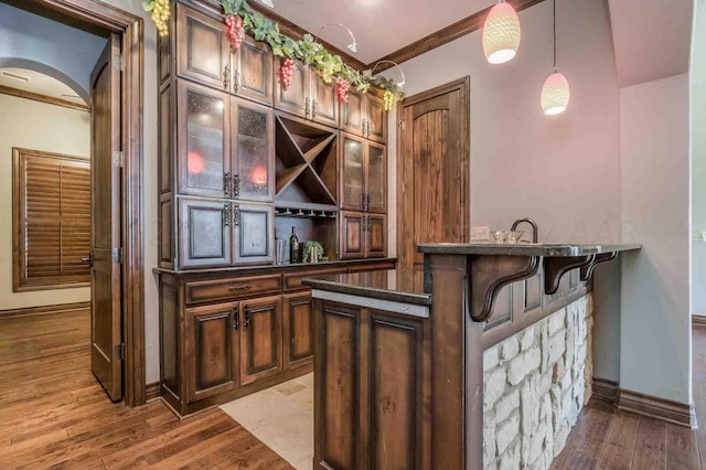 bar featuring hardwood / wood-style floors, pendant lighting, and ornamental molding