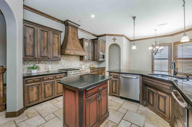 kitchen with appliances with stainless steel finishes, custom range hood, hanging light fixtures, sink, and a center island