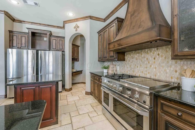 kitchen with custom range hood, appliances with stainless steel finishes, crown molding, and a kitchen island