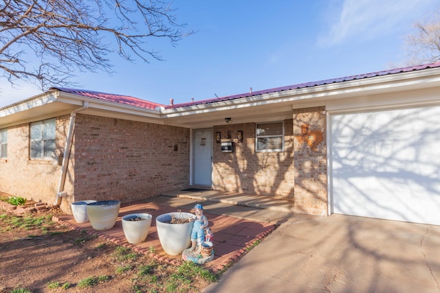 doorway to property featuring brick siding and an attached garage