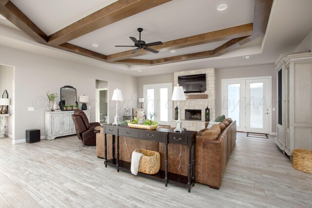 5708 Wesley Rd, Amarillo, TX 79119 - living room featuring a stone fireplace, ceiling fan, beamed ceiling, light wood-type flooring, and a tray ceiling