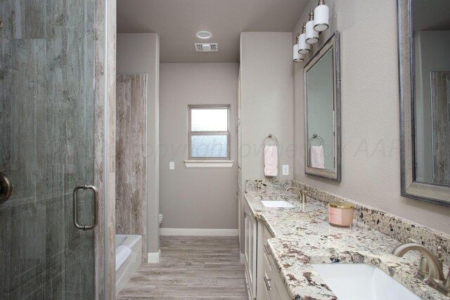 5708 Wesley Rd, Amarillo, TX 79119 - full bath with double vanity, a shower stall, wood finished floors, and a bathtub