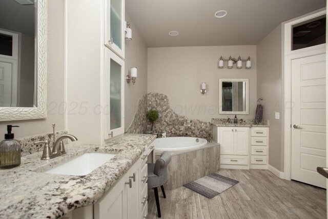 5708 Wesley Rd, Amarillo, TX 79119 - bathroom with a garden tub, two vanities, and wood finished floors
