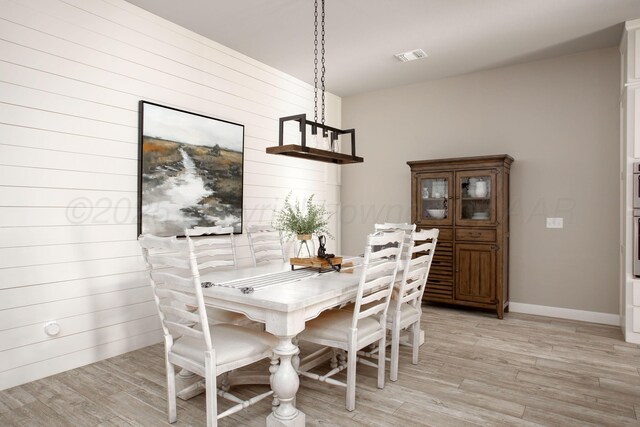 5708 Wesley Rd, Amarillo, TX 79119 - dining room featuring light wood-style flooring and wooden walls
