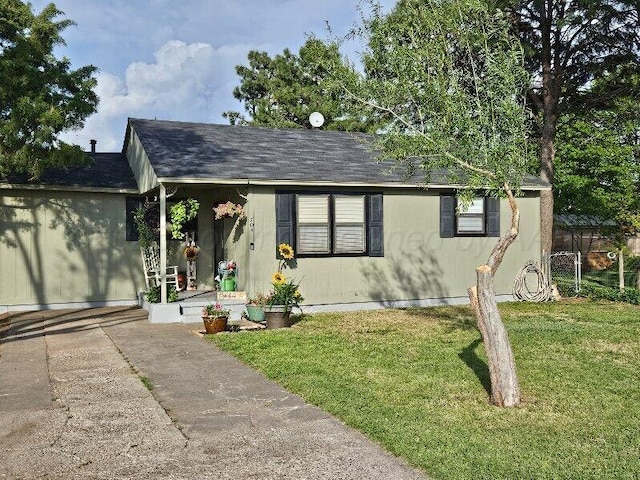 ranch-style home featuring a shingled roof, driveway, and a front lawn