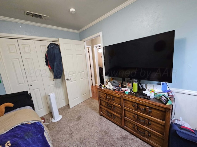 bedroom with carpet flooring, crown molding, wainscoting, visible vents, and a closet
