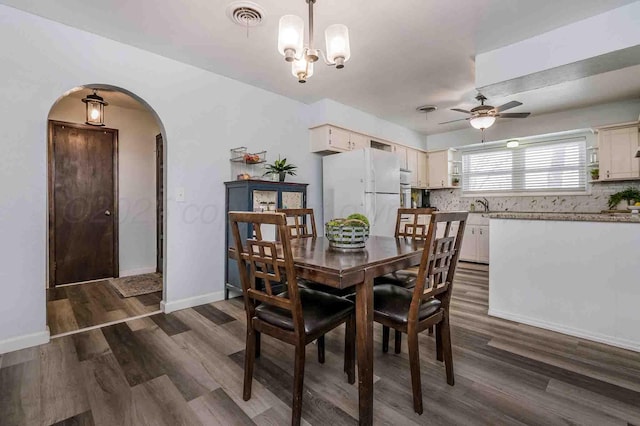 dining room featuring ceiling fan with notable chandelier, dark wood-type flooring, and sink