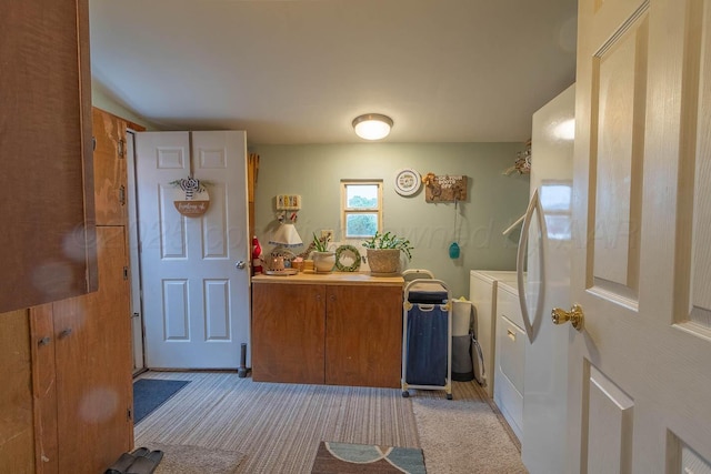 kitchen with washing machine and clothes dryer, brown cabinets, light carpet, and light countertops