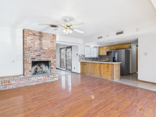 kitchen featuring stainless steel fridge with ice dispenser, open floor plan, a peninsula, backsplash, and visible vents