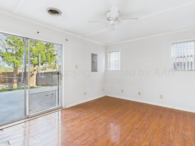 empty room featuring crown molding, electric panel, visible vents, and hardwood / wood-style flooring