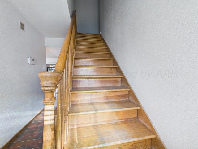 staircase with brick floor and visible vents