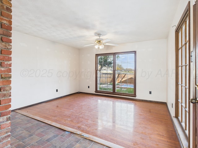 spare room featuring baseboards, wood finished floors, and ceiling fan