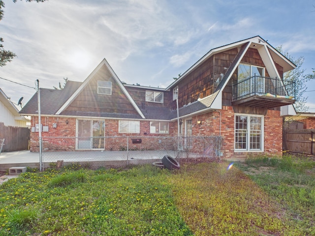 back of property with brick siding, fence, a patio, and a balcony