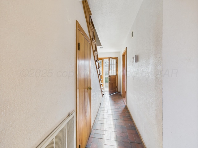 hall featuring visible vents, stairway, a textured wall, and a textured ceiling