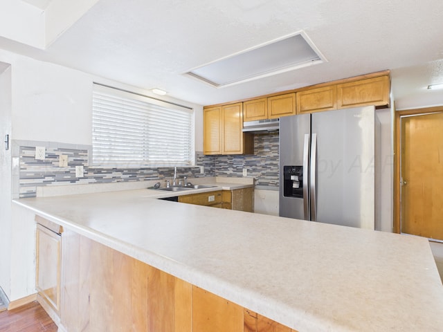 kitchen featuring stainless steel fridge with ice dispenser, tasteful backsplash, under cabinet range hood, and a sink