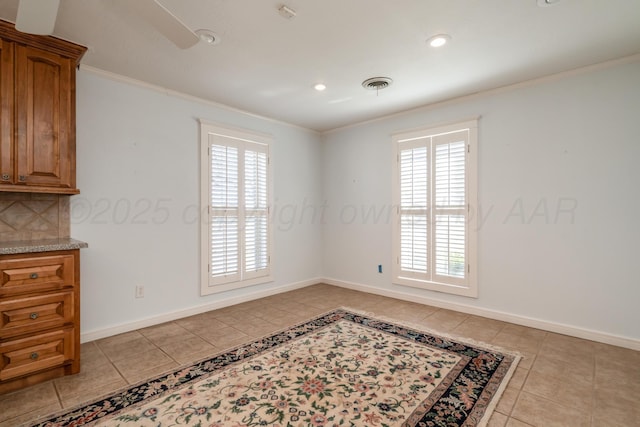 spare room with crown molding, light tile patterned floors, baseboards, and visible vents