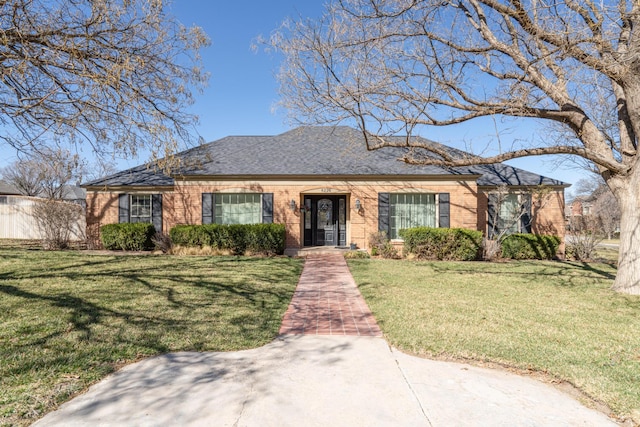 view of front facade featuring brick siding, a shingled roof, and a front lawn