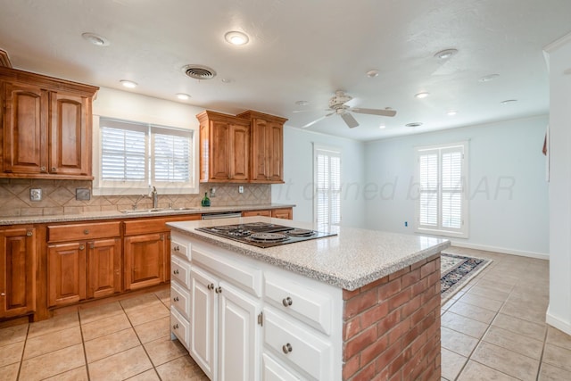 kitchen featuring light tile patterned floors, visible vents, a sink, black electric cooktop, and backsplash