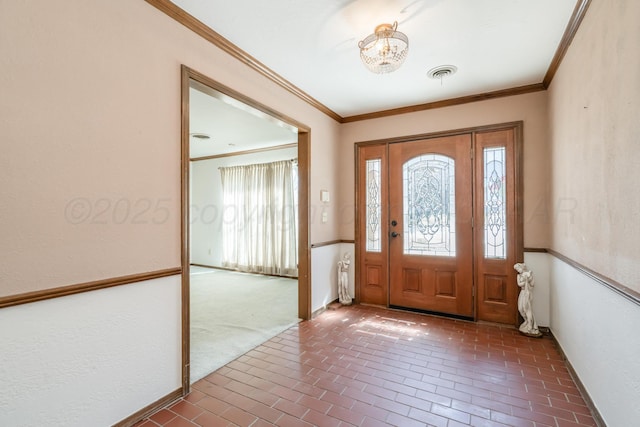 foyer featuring visible vents, brick floor, and ornamental molding