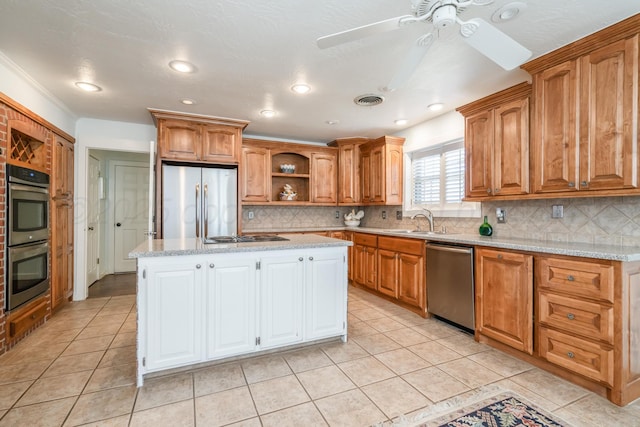 kitchen with a sink, a kitchen island, appliances with stainless steel finishes, and light tile patterned flooring