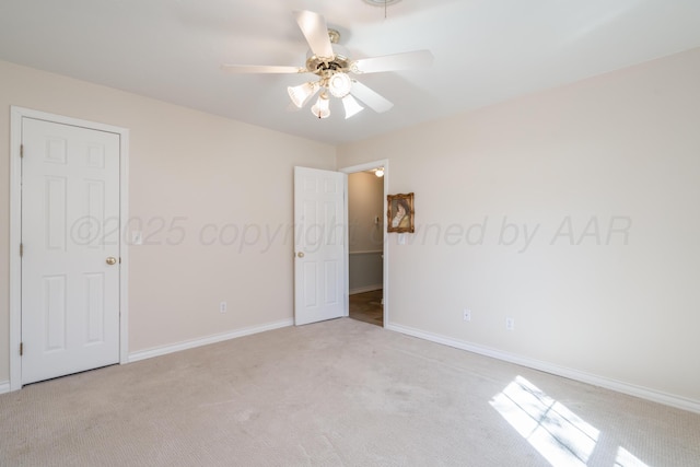 spare room featuring light carpet, ceiling fan, and baseboards