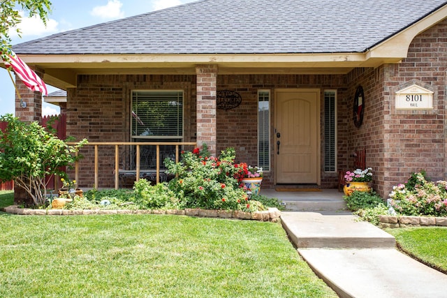8101 Vail Dr, Amarillo, TX 79118 - doorway to property with a shingled roof, brick siding, a lawn, and covered porch