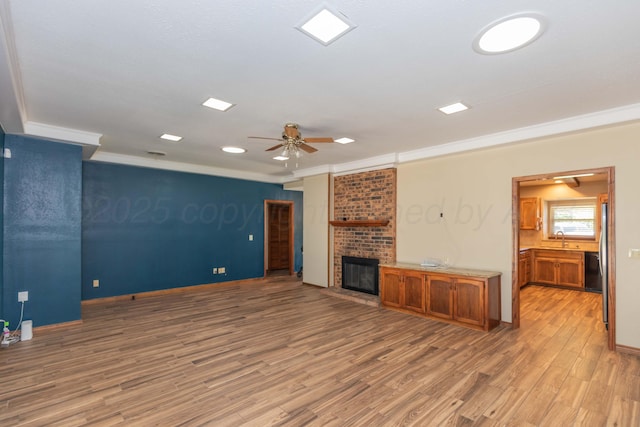 5404 While A Way Rd, Amarillo, TX 79109 - unfurnished living room featuring a ceiling fan, light wood-type flooring, crown molding, a brick fireplace, and a sink