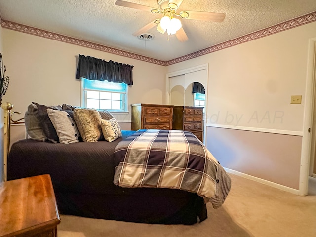 bedroom with ceiling fan, carpet floors, a closet, and a textured ceiling