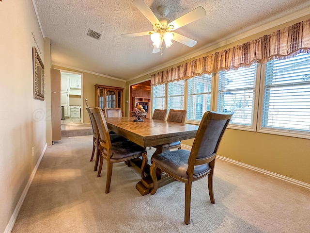 carpeted dining area featuring ceiling fan, crown molding, and a textured ceiling