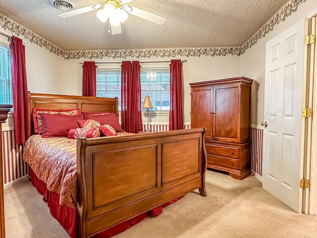 carpeted bedroom with ceiling fan and a textured ceiling