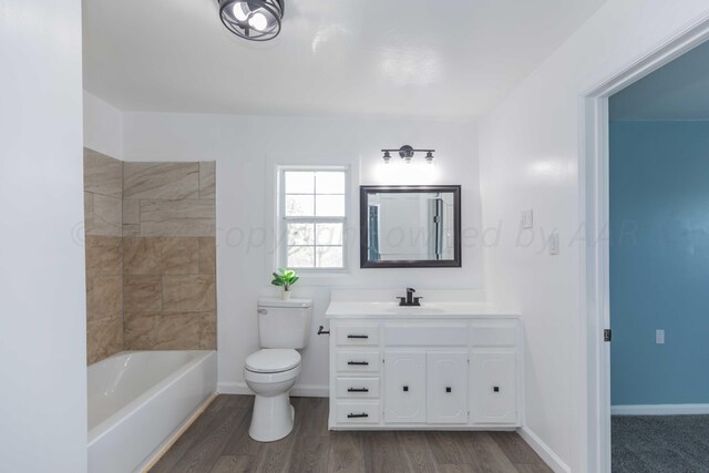 bathroom featuring hardwood / wood-style floors, a tub to relax in, vanity, and toilet